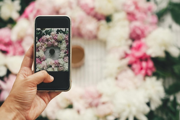 Instagram-Blogging und -Workshop Hand, die das Telefon hält und ein Foto von Kaffeegetränken in einem wunderschönen rosa und weißen Pfingstrosenrahmen auf dem flachen Tisch macht Guten Morgen Konzept Glücklicher Muttertag