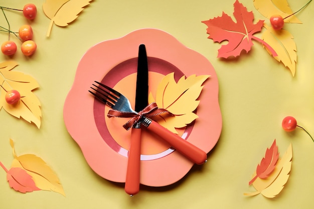 Instalação de mesa para a celebração do outono. Prato de plástico brilhante em papel amarelo com folhas de outono de papel