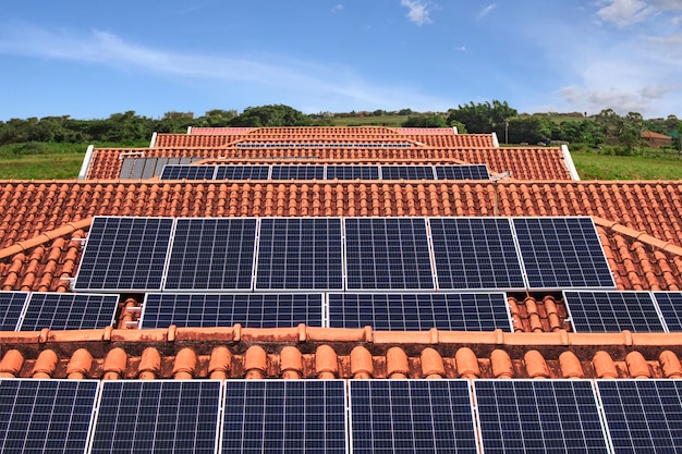 Instalação de painéis solares na cobertura de várias casas em dia ensolarado e nublado. Imagem do conceito de energia solar fotovoltaica.