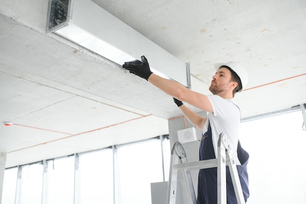 Foto instalação de sistema de aquecimento e resfriamento de armazém de tema industrial por técnico caucasiano profissional ventilação de edifícios comerciais canais retangulares distribuição de ar