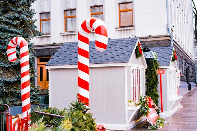 Instalación de arte de caña de Navidad y pequeñas casas decoradas en blanco instaladas en la calle de la ciudad Mercado al aire libre Diseño Decoraciones Tiendas Café Piceas árboles Vacaciones Año Nuevo Palo