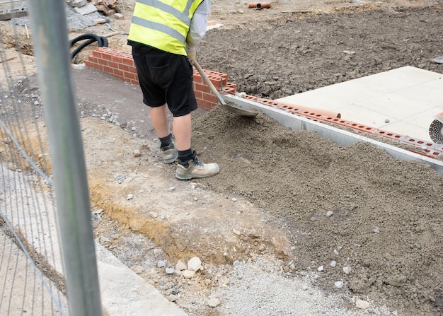 Instalación de bordillo de bordillo en hormigón semiseco durante la construcción de aceras en un nuevo sitio de construcción de viviendas