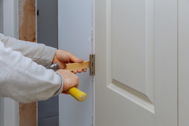 Instalación de carpintero manitas en la puerta interior de madera con martillo