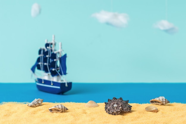 Instalación de conchas marinas en una playa de arena con el telón de fondo de un velero que se aleja. El concepto de viaje y aventura. Instalación.