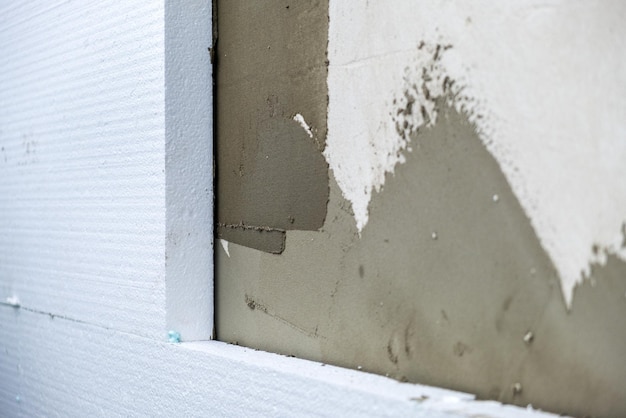 Instalación de láminas de aislamiento de espuma de poliestireno en la pared de la fachada de la casa para protección térmica.