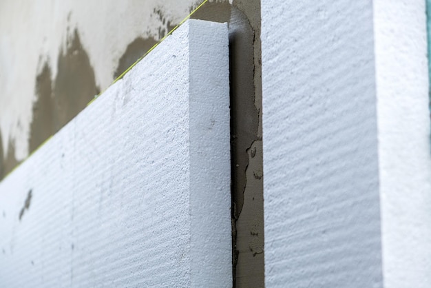 Instalación de láminas de aislamiento de espuma de poliestireno en la pared de la fachada de la casa para protección térmica.