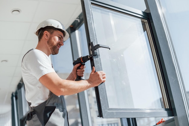 Instalación de nuevas ventanas Vista de cerca del reparador que trabaja en el interior de la habitación moderna