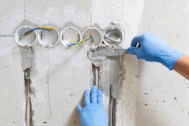 Instalación oculta de cables eléctricos para enchufes a una pared de concreto.