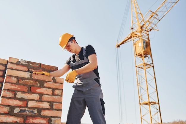 Instalación de pared de ladrillo Trabajador de la construcción en uniforme y equipo de seguridad tiene trabajo en la construcción
