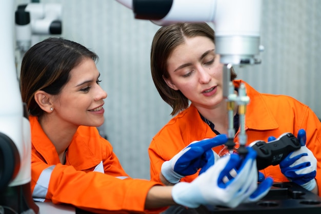 En una instalación de piezas electrónicas dos ingenieras en la planta inspeccionando y probando robótica