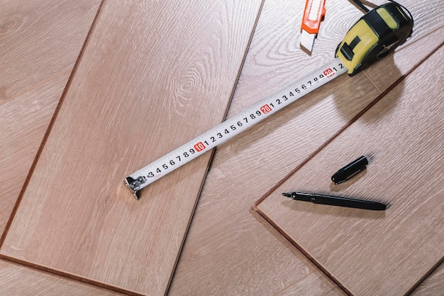 Instalación de pisos laminados en una habitación u oficina, tableros de parquet de madera y herramientas de construcción.