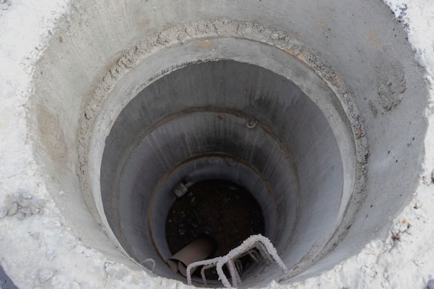 Instalación de un pozo de hormigón armado para suministro de agua y alcantarillado en una obra de construcción Primer plano de un pozo de ingeniería