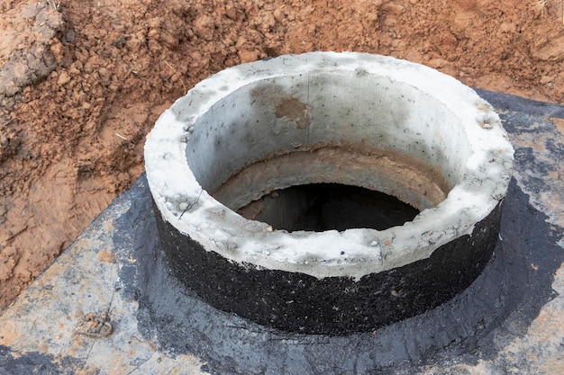 Instalación de un pozo de hormigón armado para suministro de agua y alcantarillado en el sitio de construcción Anillos de pozo con escotilla de hierro fundido y herramienta de construcción