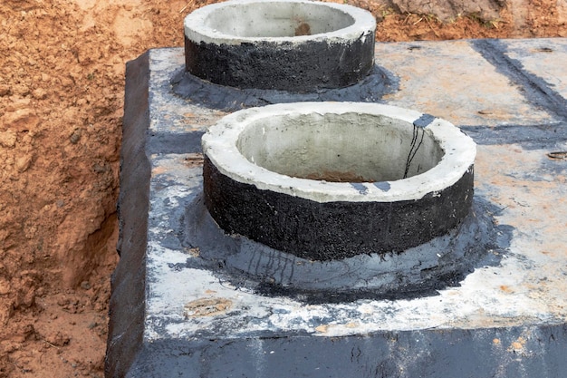 Instalación de un pozo de hormigón armado para suministro de agua y alcantarillado en el sitio de construcción Anillos de pozo con escotilla de hierro fundido y herramienta de construcción