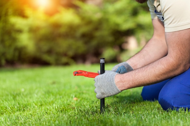 Foto instalación de rociadores de césped por un instalador profesional de sistemas de jardín caucásico.