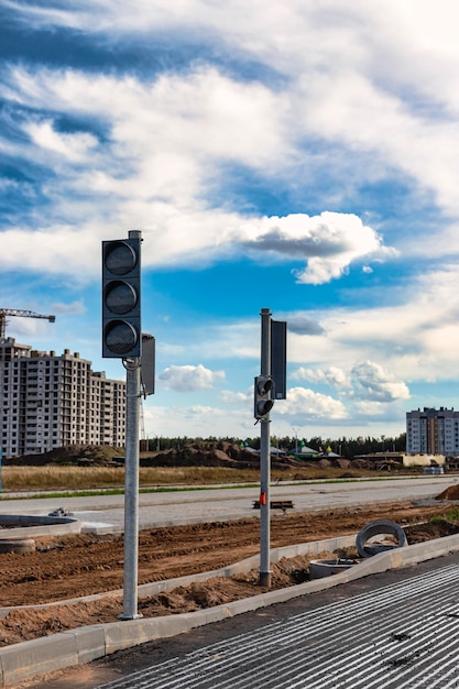 Instalación de semáforos grupales durante la construcción de una nueva intersección de tráfico y un paso de peatones en el borde de la ciudad