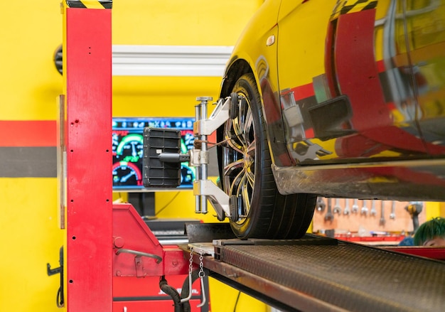 Foto instalación del sensor por el mecánico del automóvil durante el ajuste de la alineación de las ruedas en la estación de servicio de reparación