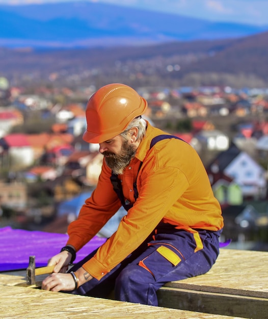 Instalación de techo plano. Techador construyendo techo nuevo. Edifició de construcción. Materiales laminados impermeables. Obras en altura. Aislamiento térmico. Superficie del techo del constructor. Techo de reparación maestro profesional.