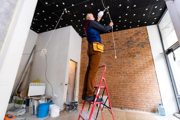 Instalador electricista con una herramienta en sus manos, trabajando con cable en el sitio de construcción. Concepto de reparación y manitas. Reconstrucción de casas y casas.