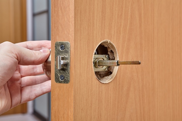El instalador empuja el eje de la manija de la puerta a través del orificio del conjunto del pestillo y el orificio frontal.