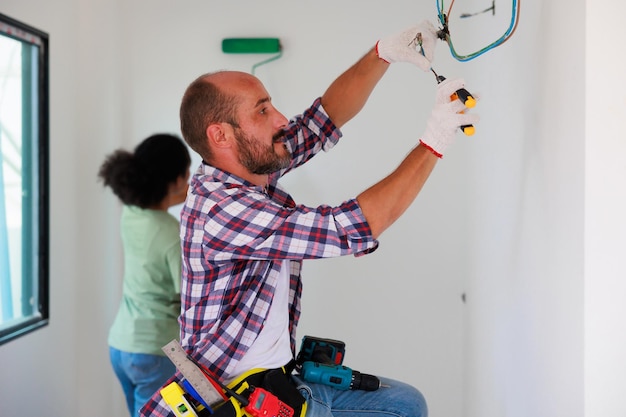 Instalador de ingeniero electricista masculino hispano con una herramienta en sus manos Pareja joven negra Servicio de mantenimiento Reparación y concepto de manitas