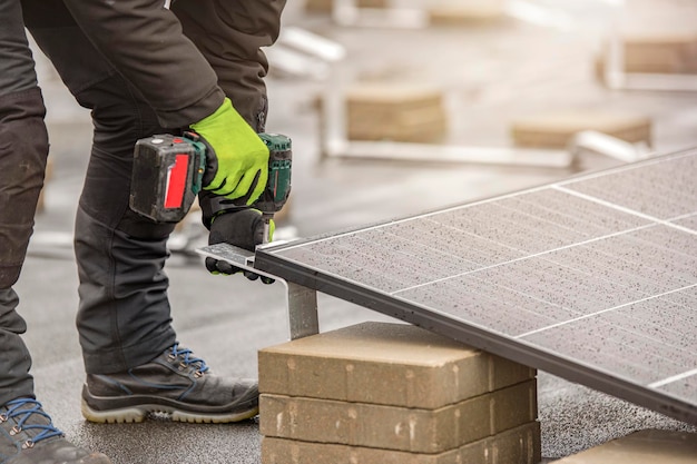 El instalador del panel solar tuerce los módulos usando sujetadores de aluminio y un taladro inalámbrico