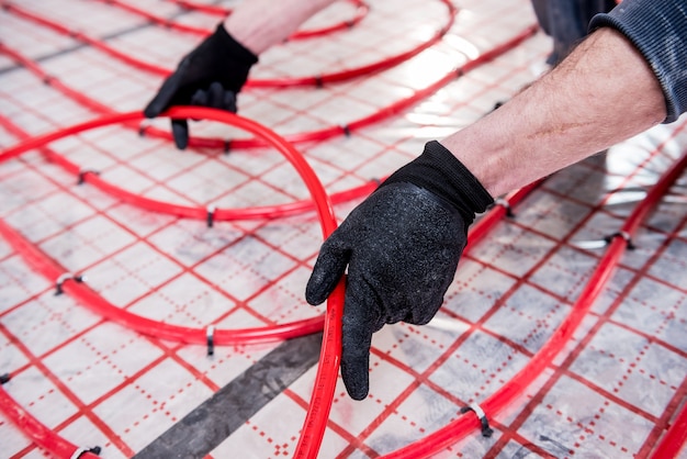 Installateur installiert das System der Fußbodenheizung zu Hause