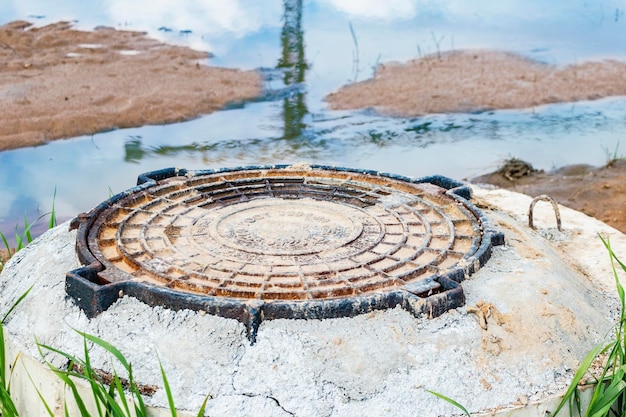 Installation eines schweren Kanalschachts aus Gusseisen auf einem Brunnen vor Pflastersteinen Kanalisation im Bau Nahaufnahme