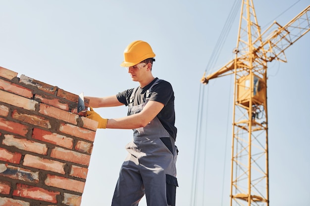 Installation von Backsteinmauern Bauarbeiter in Uniform und Sicherheitsausrüstung haben Arbeit am Bau