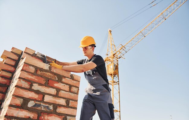 Installation von Backsteinmauern Bauarbeiter in Uniform und Sicherheitsausrüstung haben Arbeit am Bau