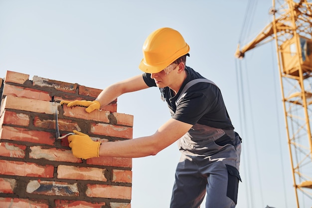 Installation von Backsteinmauern Bauarbeiter in Uniform und Sicherheitsausrüstung haben Arbeit am Bau