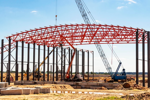 Installation von Metallbindern und -rahmen während des Baus eines Industriegebäudes oder einer Fabrik Die Arbeit von Installateuren während der Installation des Daches Bau einer großen Rahmenwerkstatt