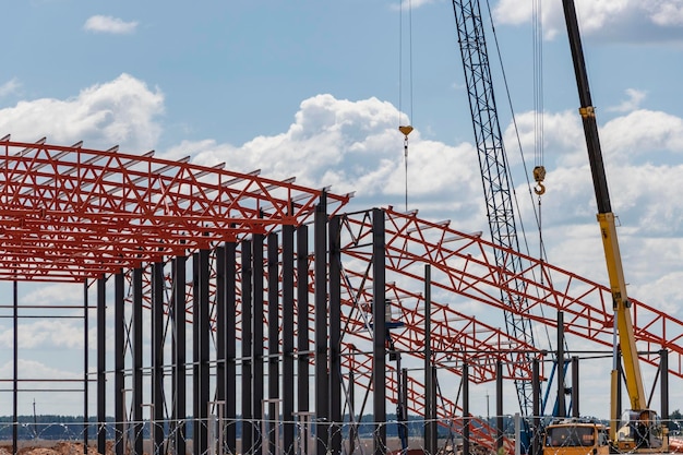 Installation von Metallbindern und -rahmen während des Baus eines Industriegebäudes oder einer Fabrik Die Arbeit von Installateuren während der Installation des Daches Bau einer großen Rahmenwerkstatt