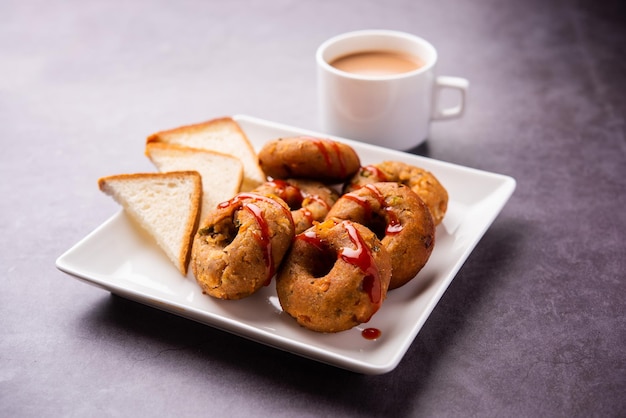 Instant Brotreste Medu Vada serviert mit Chutney und heißem Tee Indisches Frühstück oder Snack-Rezept