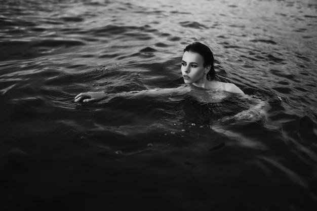 Instantánea de moda en blanco y negro de una hermosa mujer joven en el océano como papel tapiz o fondo