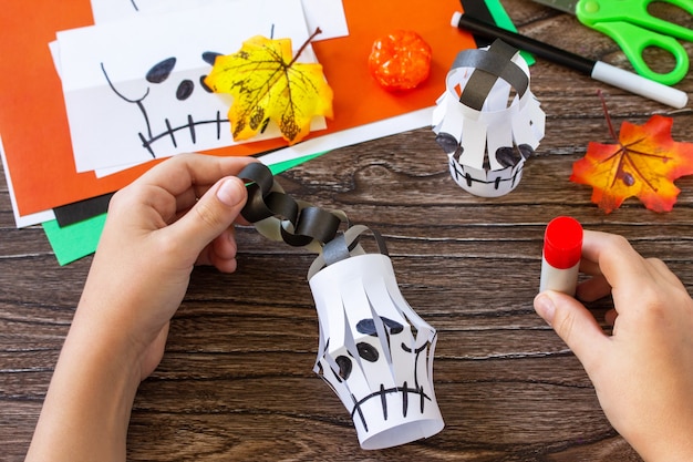 Instrução passo 8 Criança cria caveira de guirlanda de lanternas de papel para decoração de Halloween para o Halloween