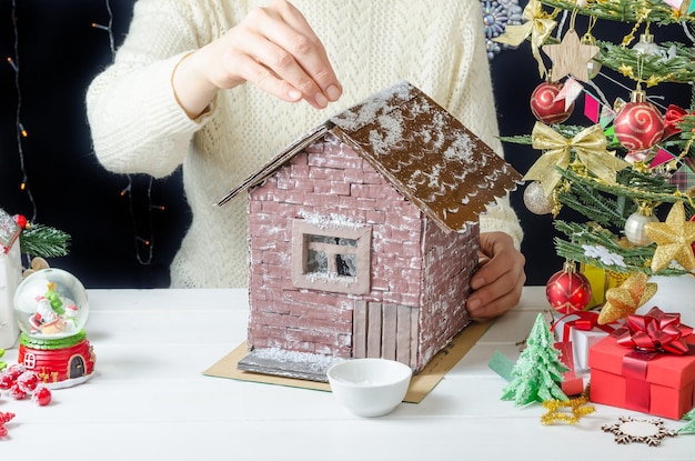 Instrucciones fotográficas paso a paso para hacer una decoración navideña una casa de cartón paso 8 espolvorear nieve artificial en el pegamento