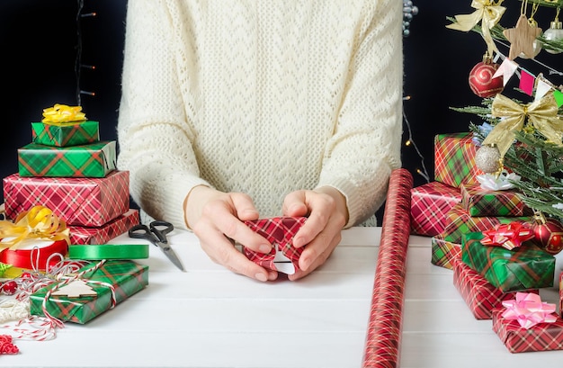 Instruções fotográficas passo a passo para embalar um presente de Natal passo 2 fixando o papel de embrulho com fita adesiva