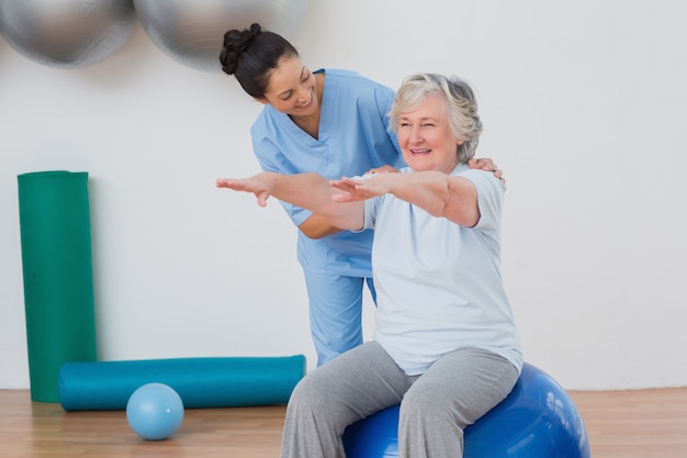 Foto instructor ayudando a mujer mayor en ejercicio