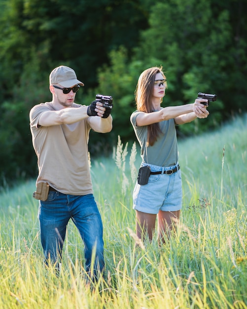 El instructor le enseña a la niña a disparar una pistola al campo