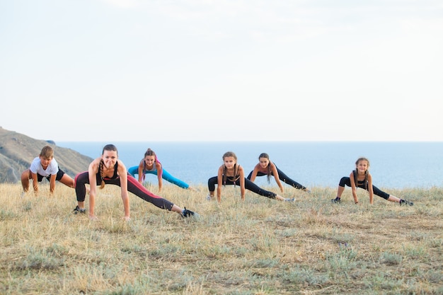 Instructor entrena a niños de yoga en las montañas en el océano.