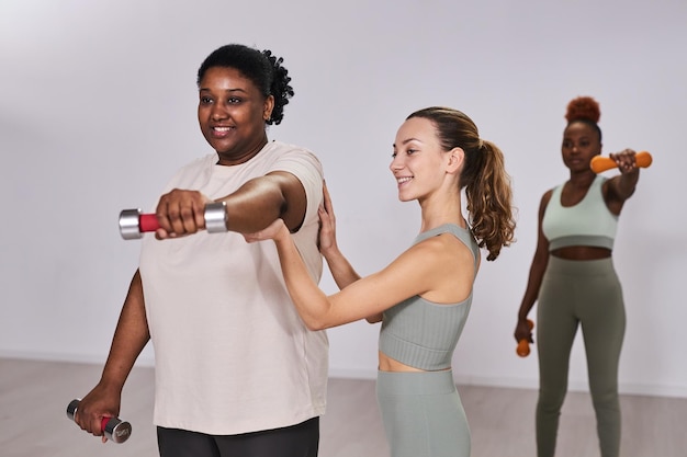 Instructor entrenando a mujer con sobrepeso en el gimnasio