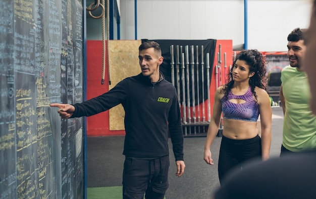 Foto instructor explicando sobre la pizarra a los atletas en el gimnasio