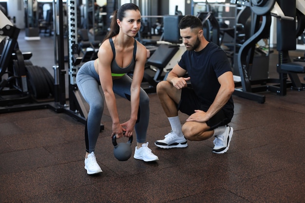 Instructor de fitness haciendo ejercicio con su cliente en el gimnasio.