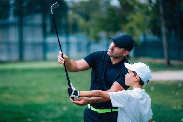 Instructor de golf ajustando el agarre del joven