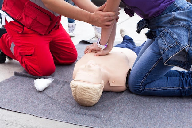Instructor guiando a una mujer para realizar RCP en el maniquí