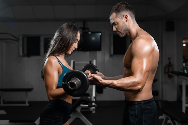 Instructor de hombre y tren de mujer, levantando pesas