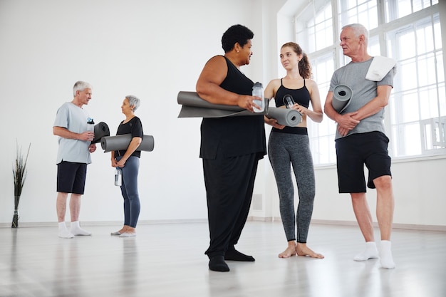 Instructor joven dando recomendaciones a personas mayores después de la clase de yoga en el estudio