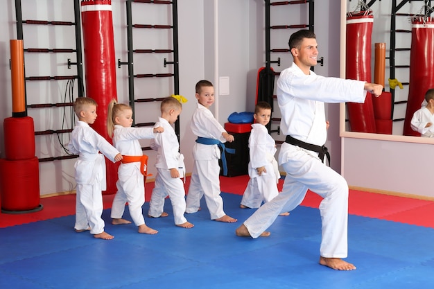 Instructor de karate masculino entrenando a niños pequeños en el dojo