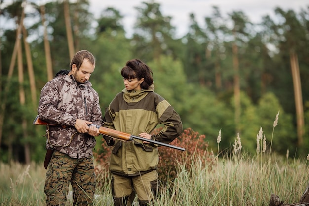 Instructor con mujer cazadora apuntando rifle a disparar naturaleza